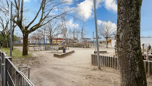 Une aire de jeux avec du sable, des bancs et des arbres.