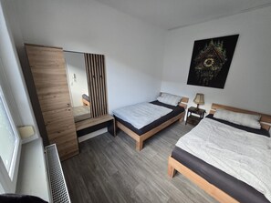 Ein modernes Schlafzimmer mit zwei Betten, einem Holzschrank, einem Spiegel und einem Wandbild.