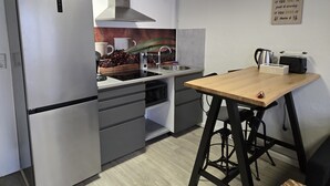 Une cuisine moderne équipée d’un réfrigérateur en acier inoxydable, d’un four encastré, d’un évier et d’une table en bois avec une chaise.