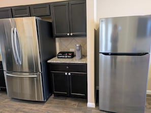 A kitchen with two stainless steel refrigerators, dark cabinets, a coffee maker, and a countertop. - A Peaceful, Toddler-Ready 4BR Home Near Austin (Austin)