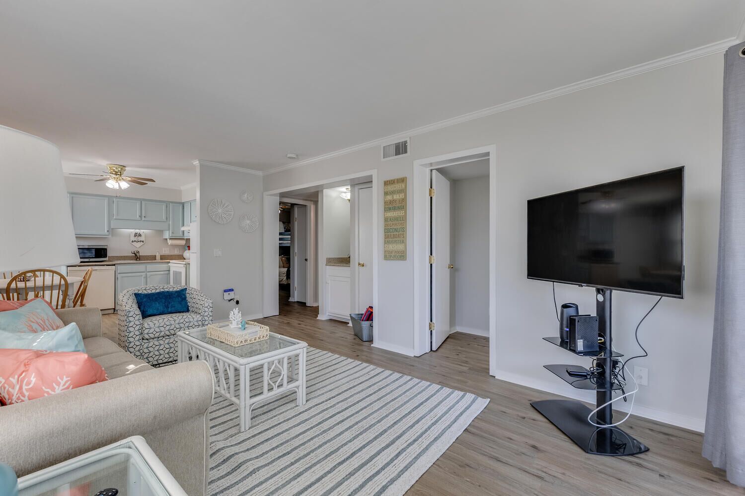 Un salon moderne avec un téléviseur à écran plat, une table basse et un canapé. Il y a également un coin cuisine équipé de placards et d’un four à micro-ondes.