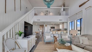 A spacious living area with a staircase, a kitchen, and a dining area. - Paradise Tides - 6 Bedroom Duplex with Community Pool (Carolina)