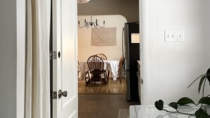 A hallway with a white door, a dining area with a table and chairs, and a refrigerator. - Lancaster Haven - Central location, fenced backyard, family friendly (Lancaster)