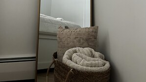 A corner of a room with a large mirror, a woven basket, and a white wall. - Lancaster Haven - Central location, fenced backyard, family friendly (Lancaster)