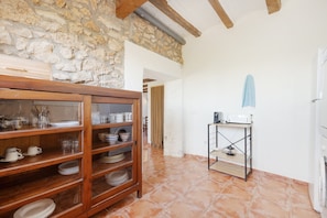 A kitchen with a stone wall, wooden shelves, and a tiled floor. - Country House 'Bahia' with Shared Pool, Wi-Fi and Air Conditioning (Deltebre)