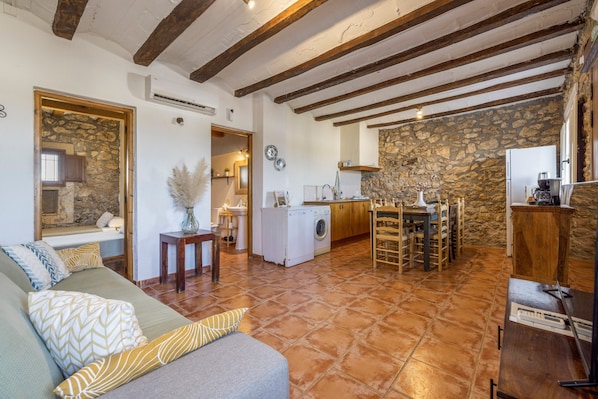 Un intérieur rustique comprenant un canapé, un lave-linge, une table à manger et un coin cuisine.