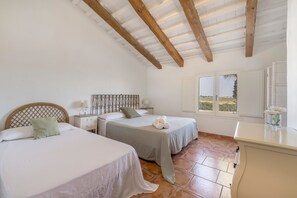 A bedroom with two beds, a wooden ceiling, a window with a view, and a bedside table with a lamp. - Country House 'Masia Llambrich Bomba' with Shared Pool, Wi-Fi and Air Conditioning (Deltebre)