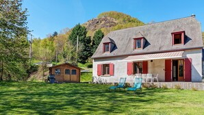 A house with a sloped roof, red shutters, and a porch with chairs. - Holiday Home 'Gite 8 Personnes, Val D'azun' with Mountain View, Private Terrace and Wi-Fi (Bun)