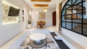 A modern interior with a seating area, a large window, and a ceiling fan. - Maha Villa Ubud  (Sukawati)