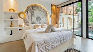 A modern bedroom with a large bed, a decorative wall mural, and a view of a pool. - Maha Villa Ubud  (Sukawati)