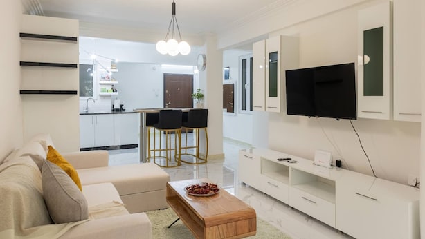 Una sala de estar moderna con un sofá, una mesa de centro y un televisor montado en la pared.