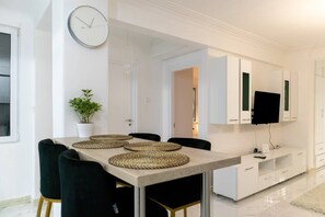 A modern dining area with a table set for four, a potted plant, and a wall-mounted clock. - A Haven in Kypseli A Basement Apartment (Athens)