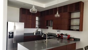 A modern kitchen with a stainless steel refrigerator, a microwave, a gas stove, and a red toaster. - Hacienda Iguana Beachfront 2BR Poolside- Costamar (Tola)