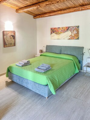 A bedroom with a bed, green bedding, a painting, and a lamp. - Dimora San Martino (Monteforte Irpino)
