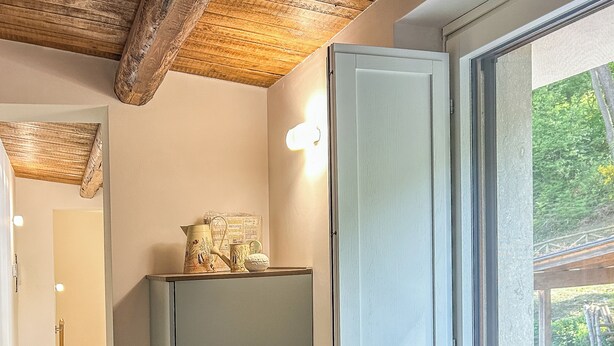 A modern kitchen with a wooden countertop, a built-in refrigerator, and a window with a view of greenery. - Dimora San Martino (Monteforte Irpino)