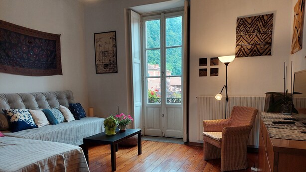 A cozy room with a bed, a sofa, a small table with plants, a chair, and a lamp. - The house on the harbor, Major: central, partial lake view, parchegggio (Mombello)