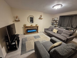 A living room with a flat-screen TV, a fireplace, a sofa, and a coffee table. - Charming Borehamwood Apartment With 2 Bedrooms (Borehamwood)