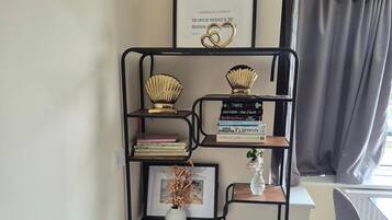 A bookshelf with books and decorative items, a framed quote on the wall, and a window with curtains.