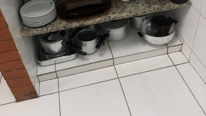 Una cocina con encimeras de granito, un lavabo y estantes con platos, tazas y utensilios de cocina.