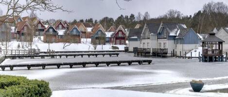 A row of colorful cabins with a frozen lake in the foreground.