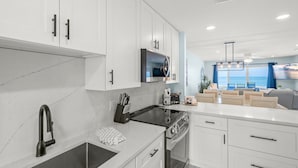 A modern kitchen with white cabinetry, a black faucet, and a built-in oven. - Coastal Comfort with Gulf-Front Views (Sarasota)