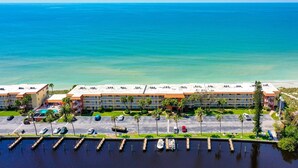 A beachfront hotel with multiple buildings, a parking lot, and a marina. - Coastal Comfort with Gulf-Front Views (Sarasota)