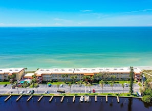 A beachfront hotel with multiple buildings, a parking lot, and a marina. - Coastal Comfort with Gulf-Front Views (Sarasota)