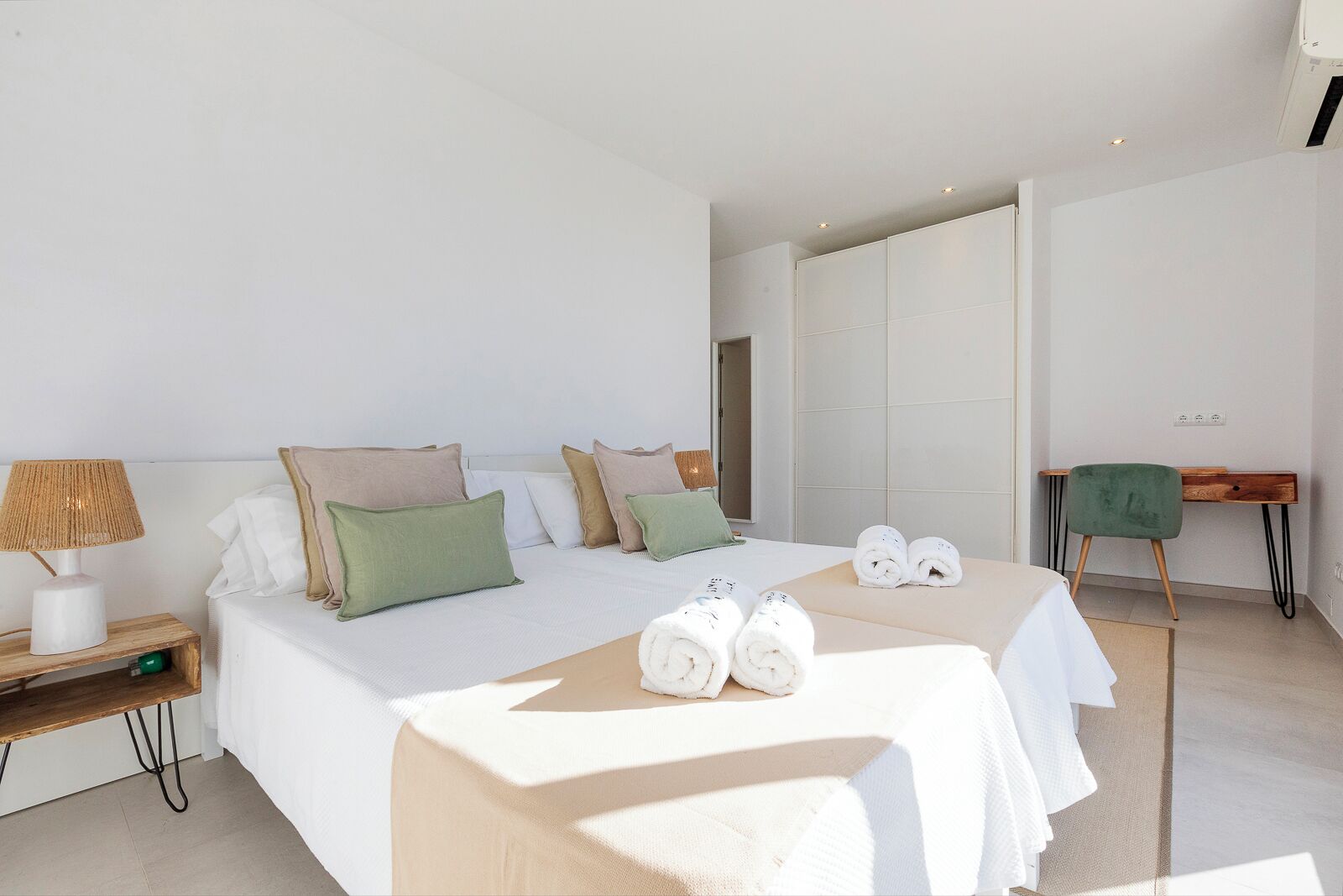 Un dormitorio moderno con una cama grande, mesitas de noche, un escritorio y un espejo.