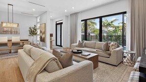 A modern living room with a sofa set, coffee table, and a dining area. - Tarpon River Enclave - New Build (Fort Lauderdale)