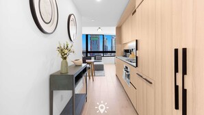 A modern kitchen with wooden cabinets, a dining area with a view of the city, and a vase with flowers on the counter. - Free Parking | Miami Gem | Smart 2BR Corner View (Miami)