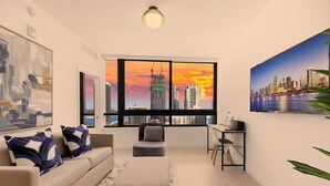 A modern living room with a large window offering a city skyline view, a sofa with patterned cushions, a small table with a speaker, and a framed abstract painting. - Free Parking | Miami Gem | Smart 2BR Corner View (Miami)