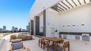 A rooftop terrace with a dining area, seating, and a city skyline view. - Free Parking | Miami Gem | Smart 2BR Corner View (Miami)