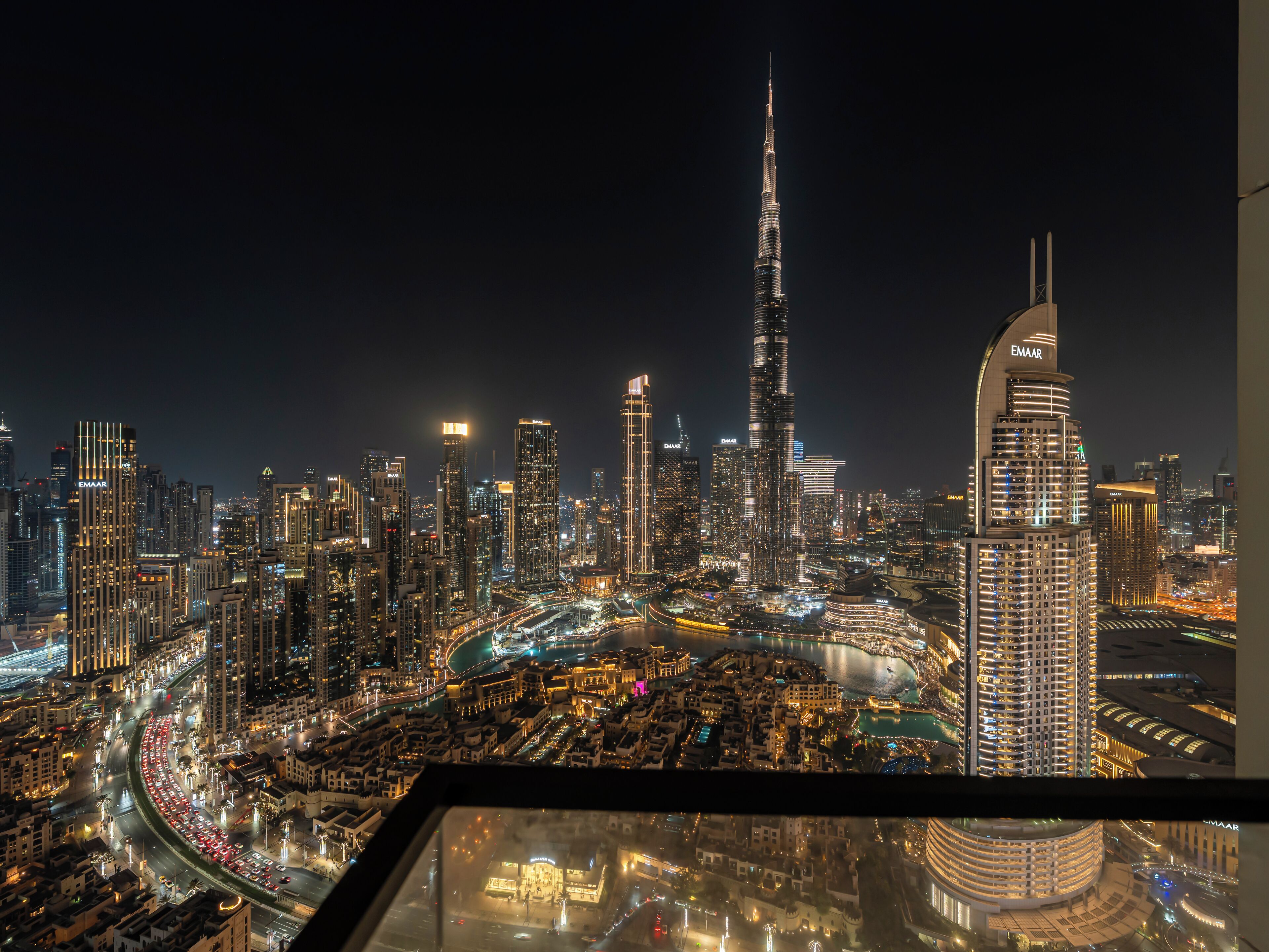 A nighttime cityscape with prominent skyscrapers, including the Burj Khalifa, and a view of the urban layout below.