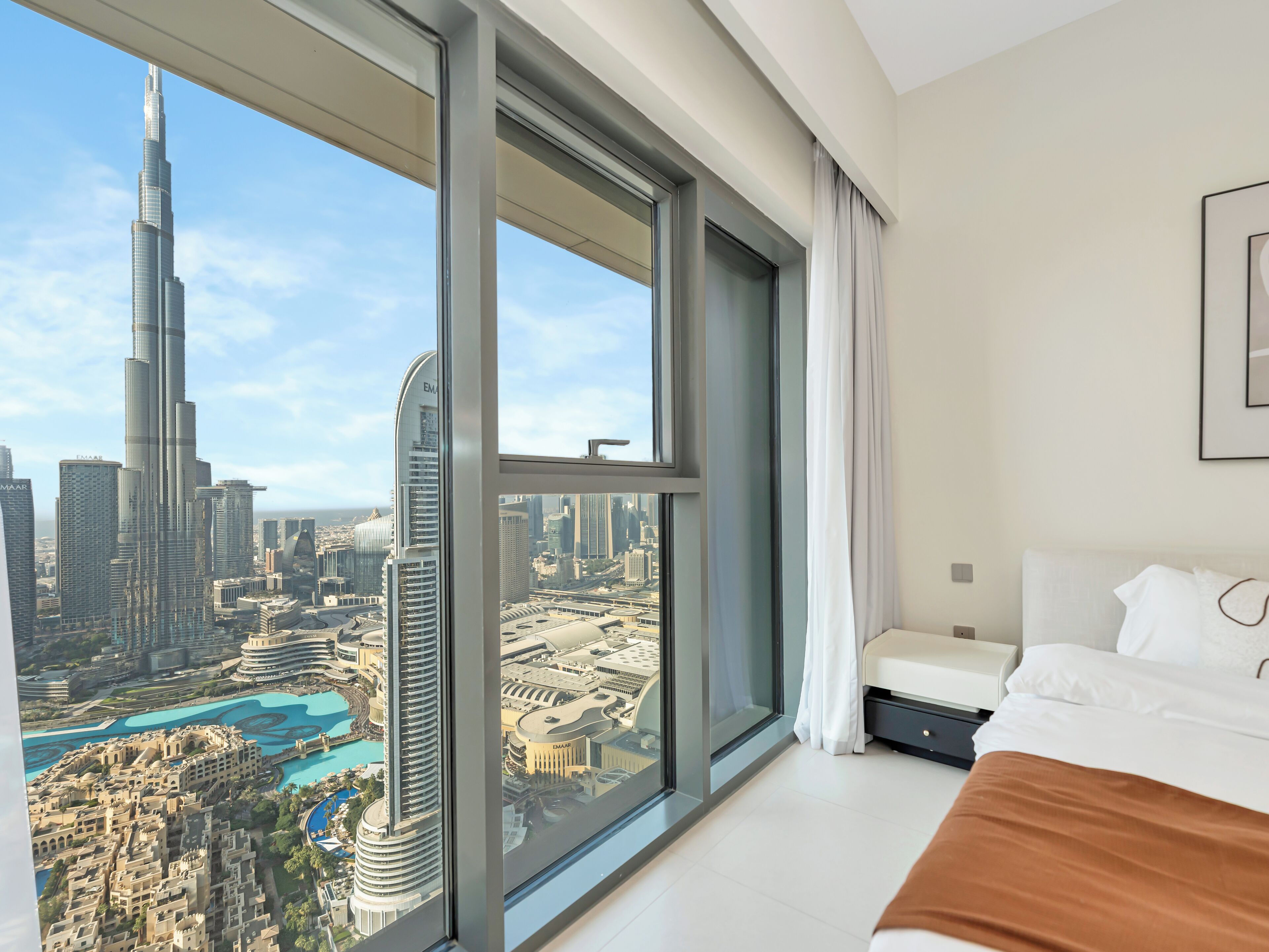 Ein Schlafzimmer mit einem großen Fenster, das einen Blick auf den Burj Khalifa und die umliegende Skyline bietet.