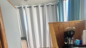 Une cuisine équipée d  ’un four à micro-ondes, d’une machine à café et de placards. Un escalier en bois mène à une chambre à coucher où se trouvent un lit et des rideaux.