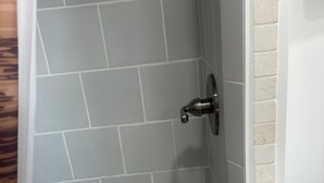 Une douche avec des carreaux gris et une porte blanche.