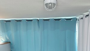 Une chambre à coucher avec un lit, des rideaux et un luminaire au plafond.