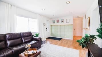 A modern living room with a leather sofa, a coffee table with a tray, and a large window.