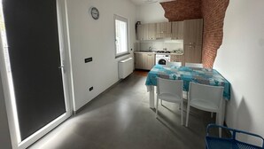 Cocina compacta con comedor, lavadora y un reloj en la pared.