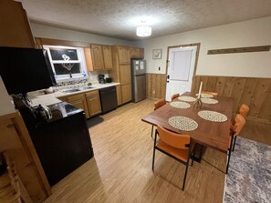 A compact kitchen with wooden cabinets, a dishwasher, a stove, and a refrigerator.