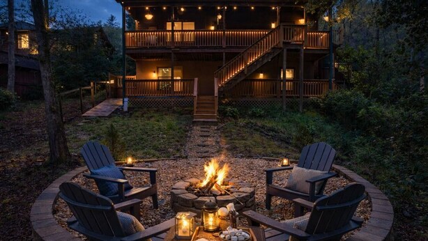 Ein gemütlicher Außenbereich mit Feuerstelle, zwei Adirondack-Stühlen und einem Tisch mit Kerzen und Snacks.