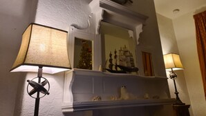 Una chimenea con un modelo de barco, un adorno de timón y un árbol de Navidad.