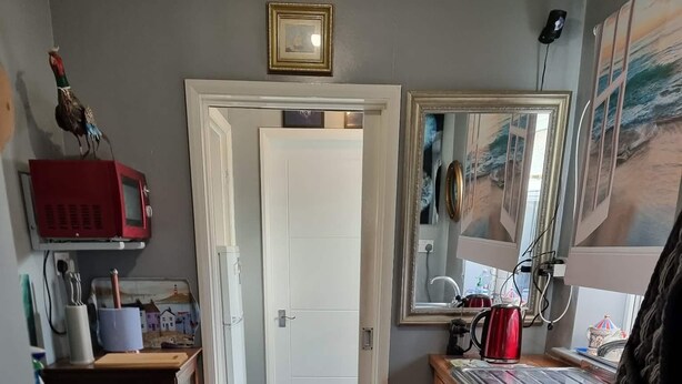 Una cocina compacta con una puerta blanca, un microondas rojo y un armario de madera.