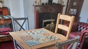 Un área de comedor con una mesa y sillas de madera, una chimenea y un sofá de cuero rojo.