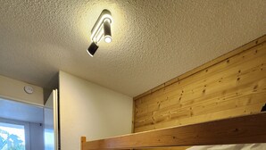Habitación con literas, cabecera de madera, una escalera y una lámpara en el techo.
