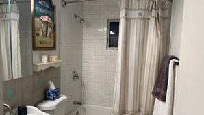 A bathroom with a shower, toilet, sink, and a towel rack. - Cozy 3BR Apartment in Peaceful Neighborhood With Kitchenette (Commack)