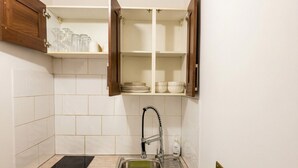 Eine Küche mit Spüle, einer schwarzen Arbeitsplatte und einem darüberliegenden Schrank.