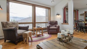 Ein gemütliches Wohnzimmer mit großen Fenstern, einem Kamin und einem Essbereich.