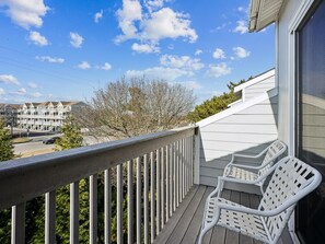 A balcony with white metal railings and two white wicker chairs.