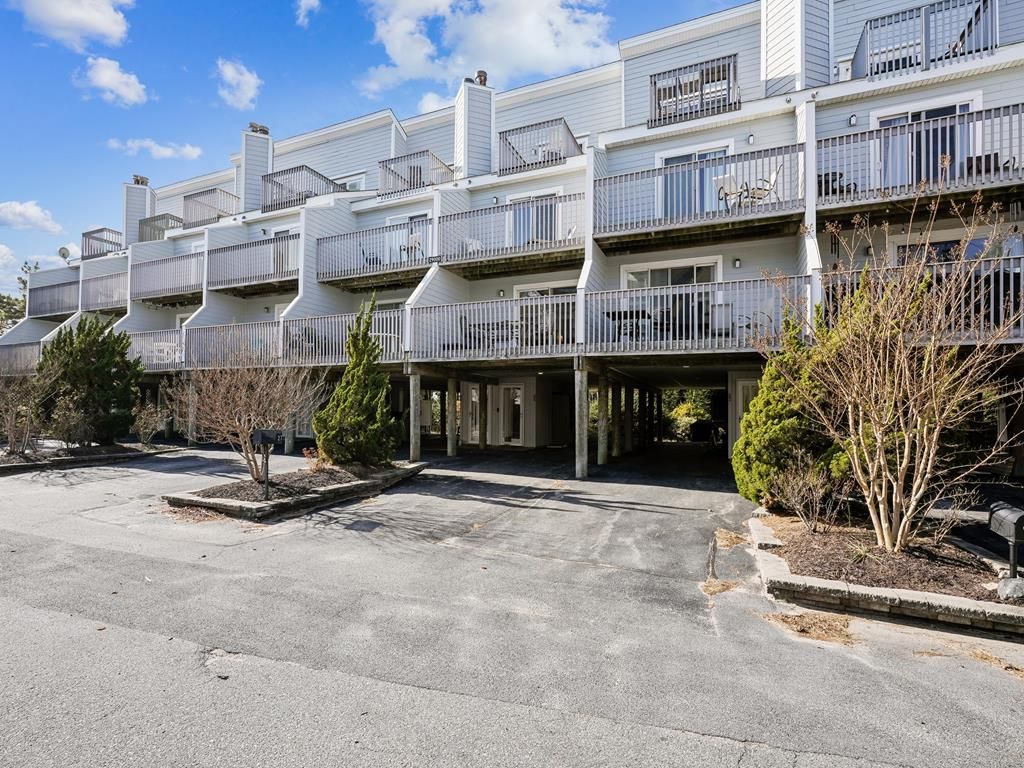 Un edificio residencial de varios pisos con balcones, estacionamiento y jardines.